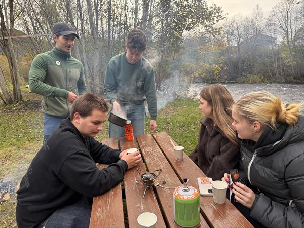 Videregåendeelever som sitter rundt et bord ute i naturen i Heim kommune.