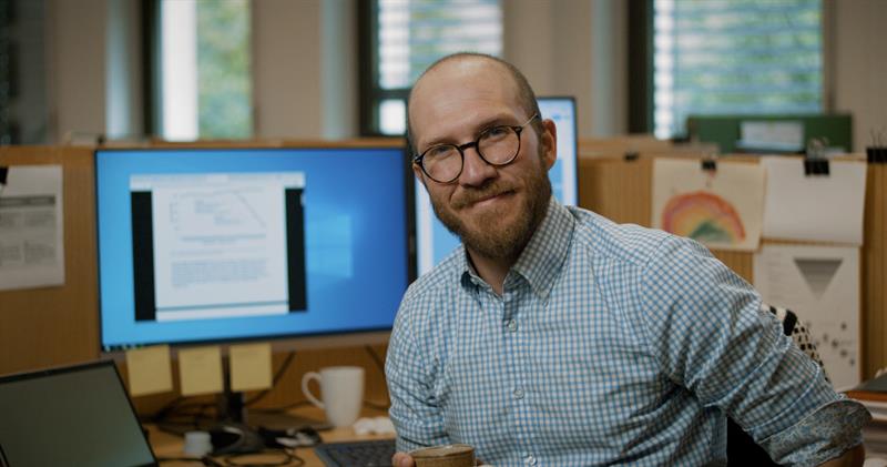 Mann på kontor. Foto Jon Skår en mann på et kontor står og holder en kaffekopp. Foto: Berre