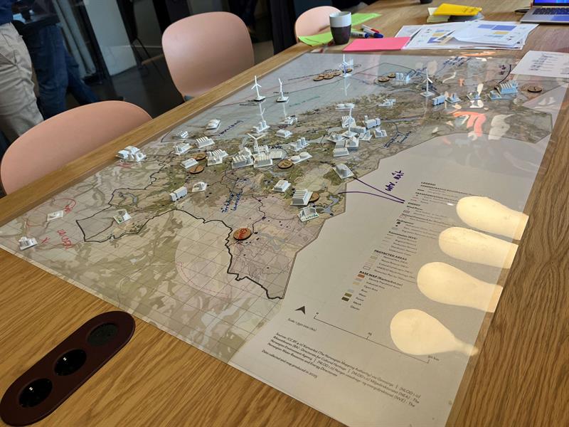 Små modeller av kraftproduksjon og forbruk står i et fysisk kart på et bord. Foto Sivert Spalder.