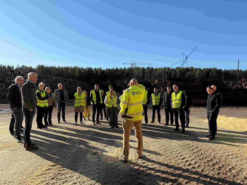 Virkessjef Sverre Luktvasslimo i Inntre Kjelstads snakker til ei gruppe på 20 stykker som står i en halvsirkel foran ham. Foto: Ida Valsø, Trøndelag fylkeskommune.
